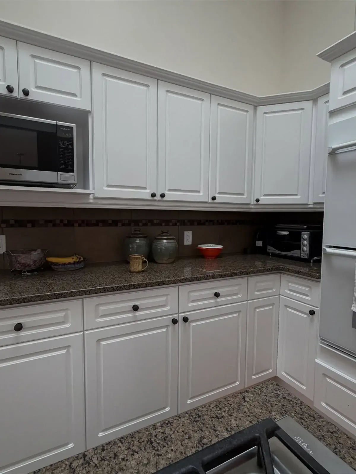 Crisp white refinished kitchen cabinets with granite counters by Chamos Painting