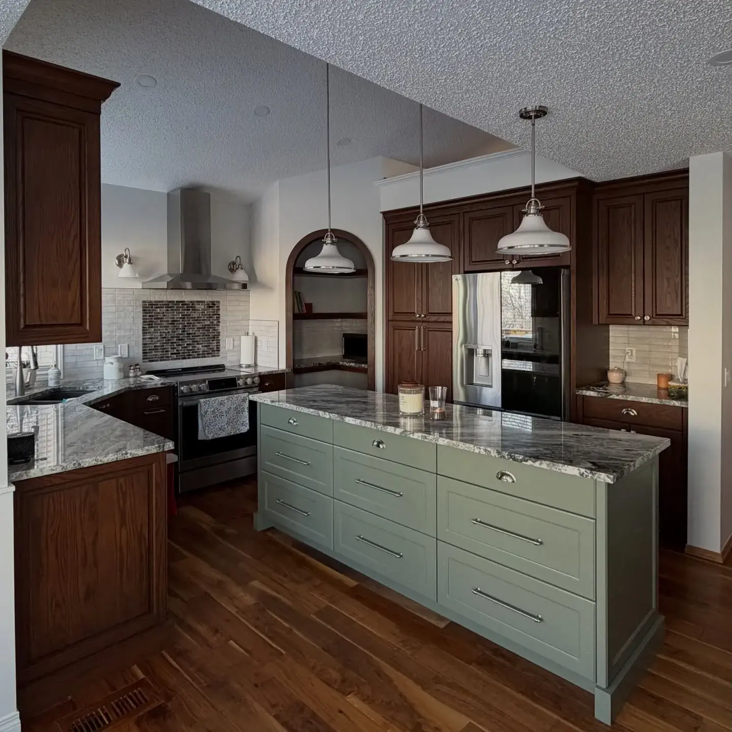 Professional kitchen repaint showcasing rich wood cabinets, a sage-green island, and crisp trim