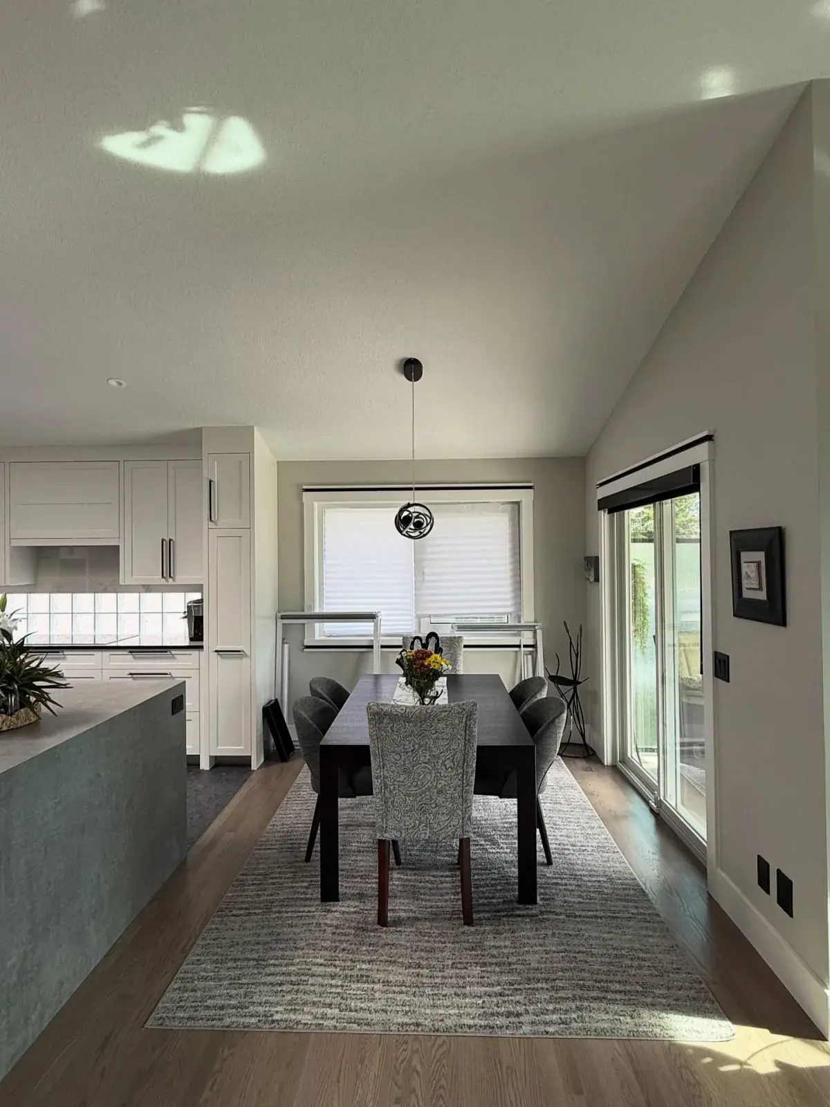Open-concept dining area with vaulted ceiling beside a freshly painted white kitchen in a Calgary home